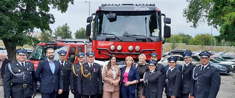 Grupa strażaków pozujących z nowymi samochodami ratowniczo-gaśniczymi