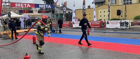 Strażacy pokonujący tor przeszkód w pełnym umundurowaniu podczas zawodów Toughest Firefighter