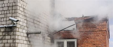 Zdjęcie dymiącego budynku mieszkalnego po pożarze.