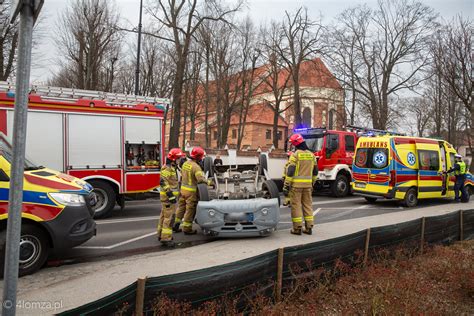 Zdjęcie samochodu po dachowaniu na ulicy, z widocznymi służbami ratunkowymi