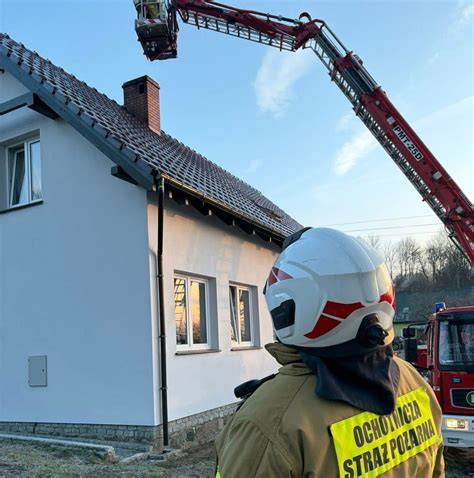 Strażacy gaszący pożar komina domu jednorodzinnego