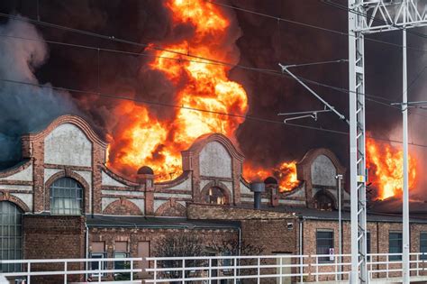 Zdjecie dawnego budynku kolejowego objętego pożarem we Wrocławiu z widocznym dymem i strażakami