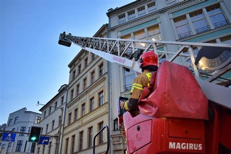 Strażacy usuwający sople z dachu budynku