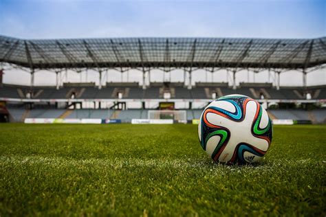 Piłka nożna na boisku sportowym z intensywnie użytkowanym trawnikiem