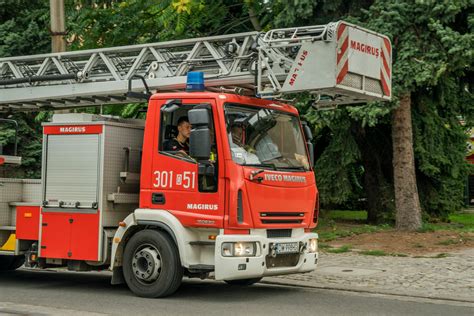 Wóz strażacki z wysuniętą drabiną przed płonącą kamienicą w centrum miasta