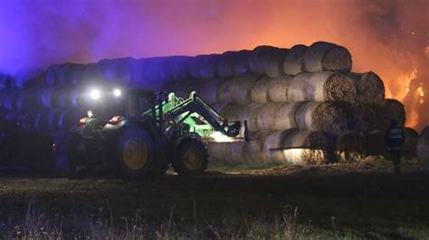 Zdjęcie strażaków gaszących płonące bele słomy na drodze