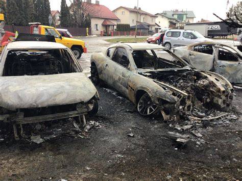 Zniszczone samochody po pożarze, widok na trzy spalone wraki aut