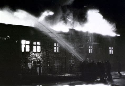 Scena płonącej hali stoczni podczas koncertu z widoczną paniką i ewakuacją ludzi