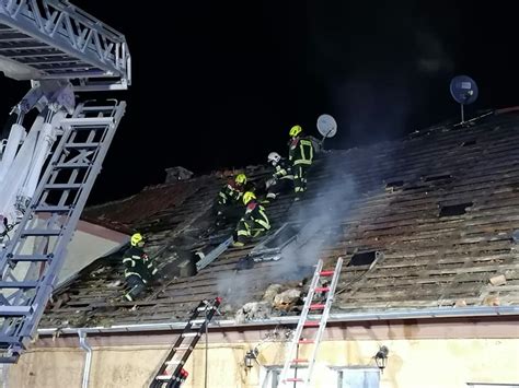 strażacy gaszący pożar poddasza budynku wielorodzinnego