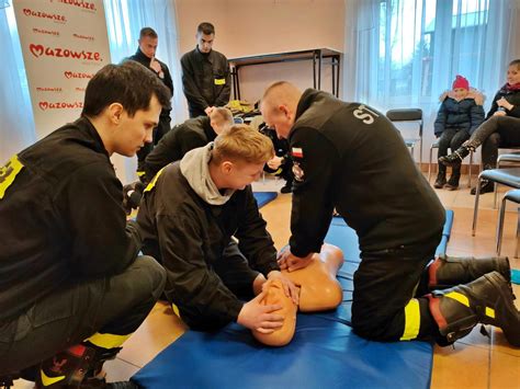 Grafika przedstawiająca szkolenie strażaków z zakresu udzielania pierwszej pomocy i obsługi defibrylatora AED