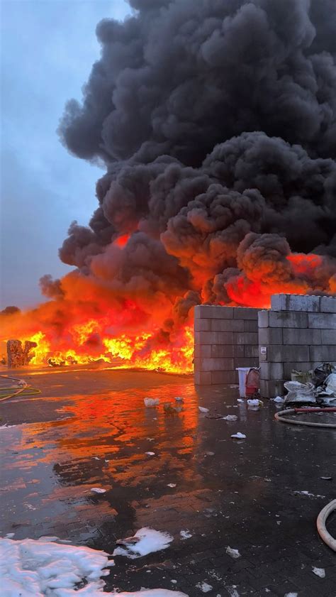 Strażacy gaszący pożar w zakładzie przemysłowym, widok z zewnątrz