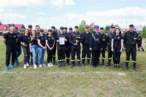 Zdjęcie grupowe strażaków biorących udział w zawodach sportowo-pożarniczych na boisku wiejskim