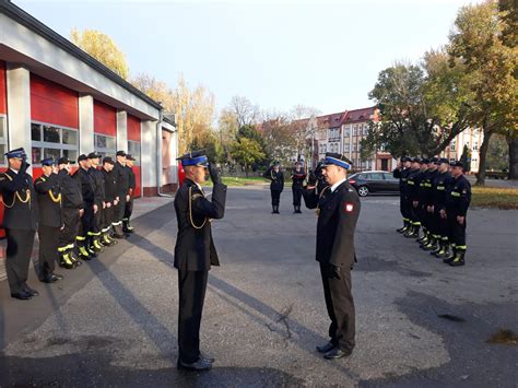Młodzież w mundurach strażackich i policyjnych podczas uroczystego apelu przed budynkiem szkoły w Małopolsce