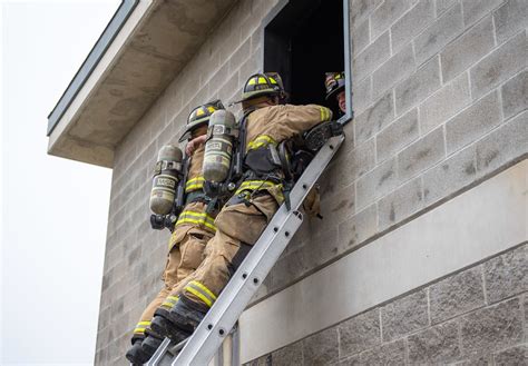 Thematic photo of firefighters at a building fire, showing a ladder or rescue operation in a residential area.