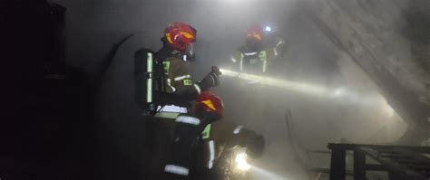 Strażacy z aparatami oddechowymi w zadymionym pomieszczeniu