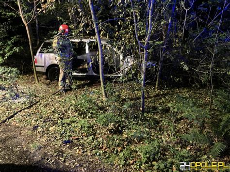 Zdjęcie płonącego samochodu osobowego w lesie, z widocznymi służbami ratunkowymi