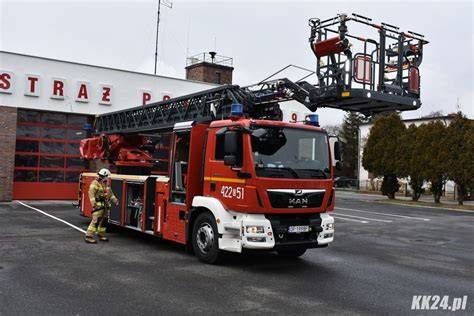 Wóz strażacki z rozłożoną drabiną mechaniczną w akcji gaśniczej