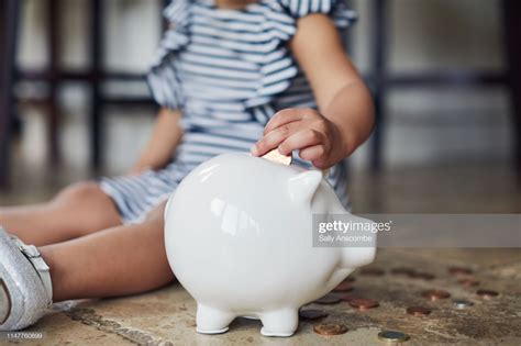 Thematic photo of a child putting coins into a piggy bank with a fire truck motif