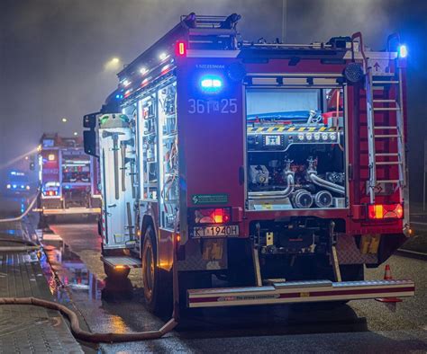 Zdjęcie przedstawiające akcję gaśniczą w nocy, z widocznymi płomieniami i sylwetkami strażaków