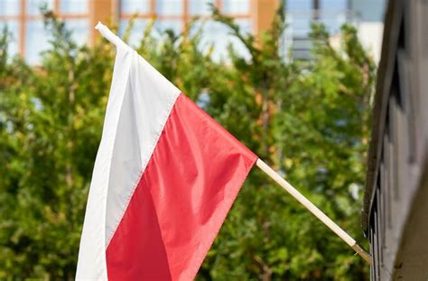 Zdjęcie przedstawiające oficjalną flagę Związku OSP RP wywieszoną na maszcie przed remizą strażacką