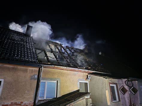 Strażacy gaszący pożar poddasza budynku wielorodzinnego nocą
