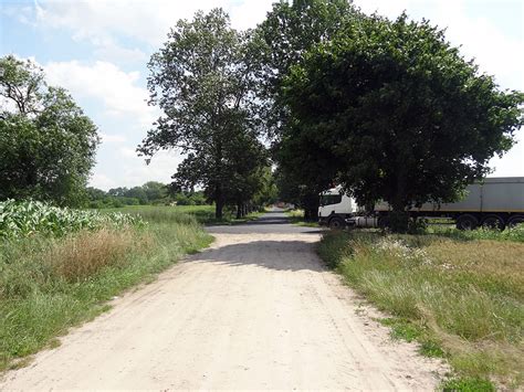 Zalana droga gruntowa w Piaskach, widoczne kałuże i ślady degradacji nawierzchni.