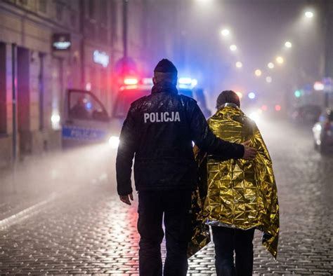 Policjant wyprowadzający osobę starszą z zadymionego budynku