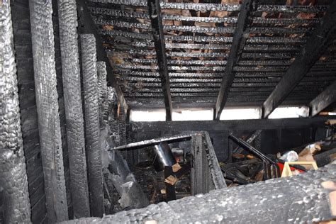 Residential building after a fire in the attic, showing fire damage to the roof structure.