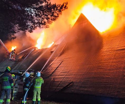 Zdjęcie strażaków walczących z płomieniami w nocy w dużej hali