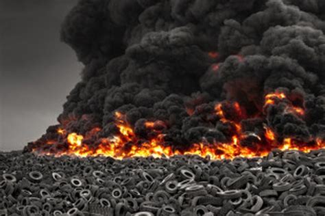 Thematic photo of firefighters battling a large tire fire, with thick black smoke