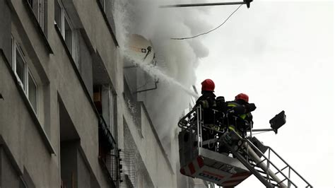 Strażacy gaszący pożar w oknie bloku mieszkalnego