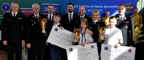 Grupa laureatów turnieju wiedzy pożarniczej z wręczającymi nagrody, w tym brygadier Marek Szymanek
