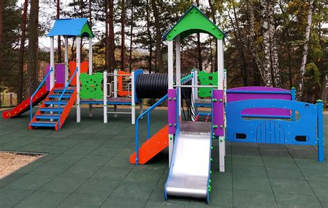 Wysoka, kolorowa wieża strażacka na placu zabaw z różnymi elementami do wspinaczki i zjeżdżania.