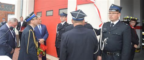 Grupa strażaków w mundurach przed remizą strażacką w Pisarzowicach świętująca jubileusz.