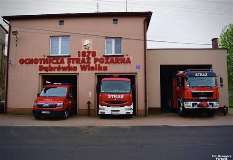 Zdjęcie strażaków OSP Dąbrówka Wielka w umundurowaniu, przed odnowioną strażnicą, podczas obchodów 100-lecia