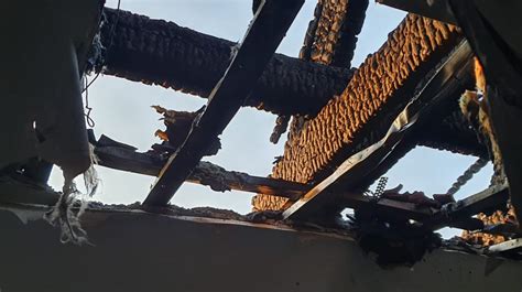 Strażacy dogaszający zniszczoną konstrukcję dachu po pożarze budynku przemysłowego