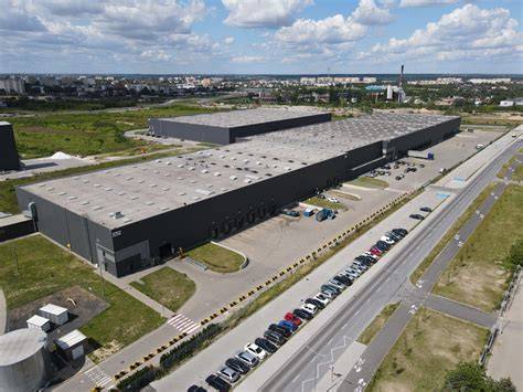 Zdjęcie hali magazynowej dawnych zakładów samochodowych, z widocznym zadymieniem lub strażakami