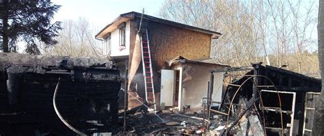 Strażacy gaszący pożar poddasza domku letniskowego, widoczne dym i zniszczenia dachu