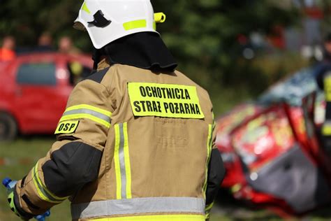 Strażak ochotnik niosący starszą kobietę z płonącego budynku