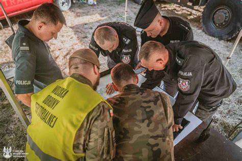 Tematyczne zdjęcie strażaków-ochotników w akcji ratowniczej z tłem lokalnej społeczności