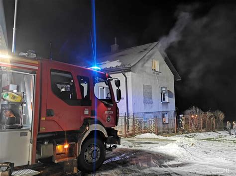 Zdjęcie przedstawiające nocną akcję gaśniczą w budynku mieszkalnym lub gospodarczym w Strzebiniu, z widocznymi wozami strażackimi i dymem