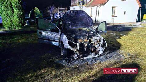 zdjęcie wozów strażackich gaszących pożar samochodu w nocy