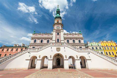 Zamość, historyczna panorama miasta z zabudowaniami, w tle nowoczesny budynek szkoły