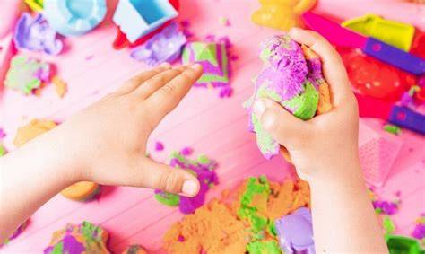 zdjęcie różnokolorowej ciastoliny Play-Doh i dziecięcych rąk bawiących się nią