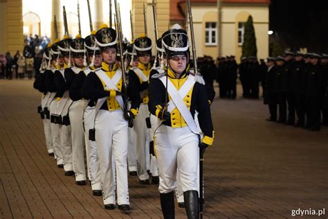 Ilustracja przedstawiająca strażaków w historycznych mundurach podczas uroczystości patriotycznej
