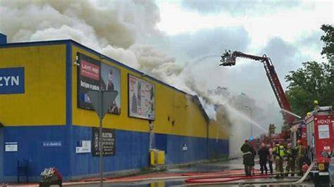 Strażacy gaszący pożar marketu Lidl w Radomsku, z widocznym zawalonym dachem