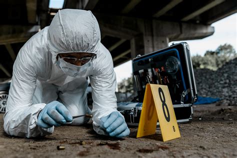 Photo of police investigators examining a crime scene with burnt vehicles, focusing on forensic evidence.
