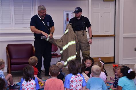 Photo of firefighters reading to children or demonstrating equipment