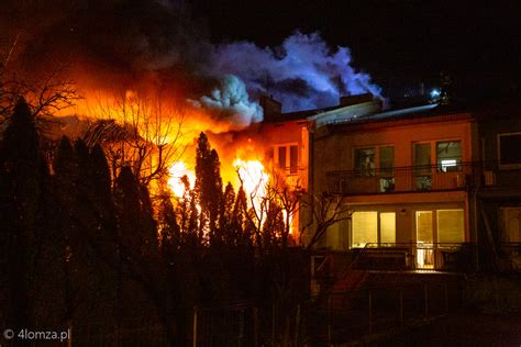 Zdjęcie przedstawiające nocny pożar domu jednorodzinnego, z widocznymi płomieniami i dymem.