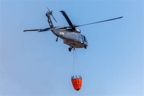 Śmigłowiec Black Hawk z podwieszonym zbiornikiem bambi bucket podczas zrzutu wody na pożar w górach Turcji
